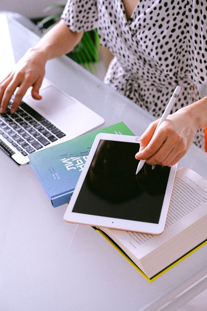 why-choose-us Woman multitasking with a laptop and tablet at a home office, showcasing remote work efficiency.
